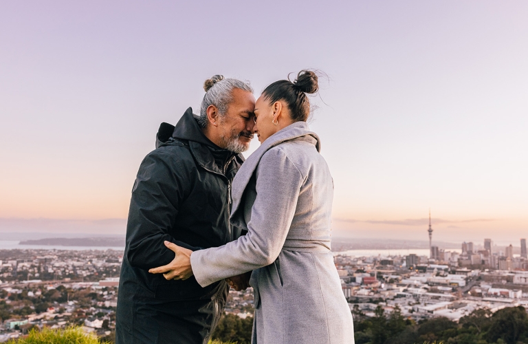 Man and woman hongi with Auckland City in background