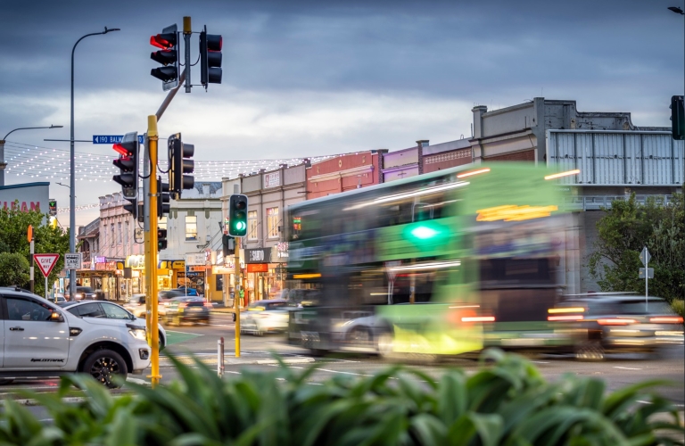A busy street intersection in Auckland with traffic passing by. 