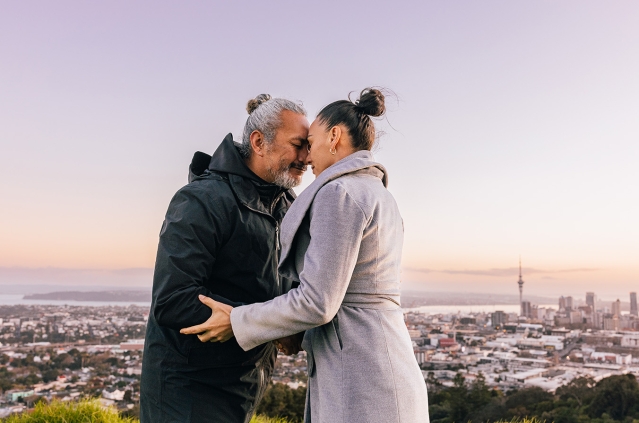 Man and woman hongi with Auckland City in background
